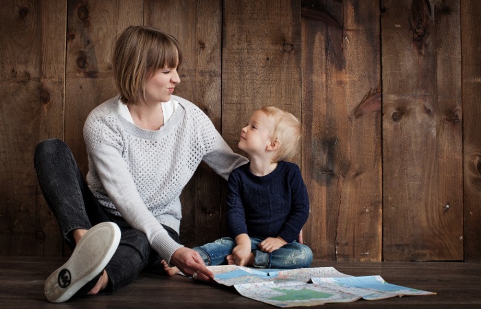 Mother and young son sitting on the floor smiling at each other